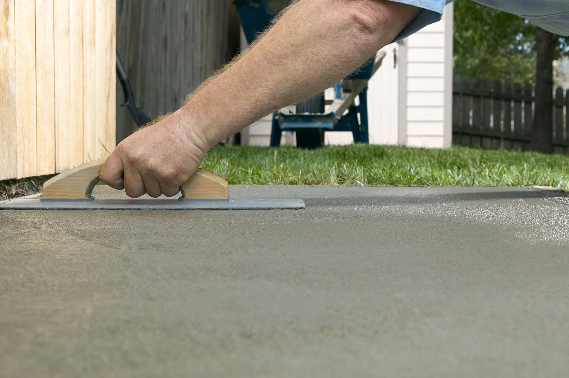 Person screeding wet cement in a backyard project - CA Plasterers